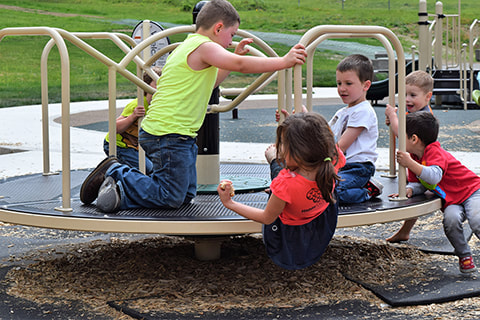 Kids on playground merry-go-round.